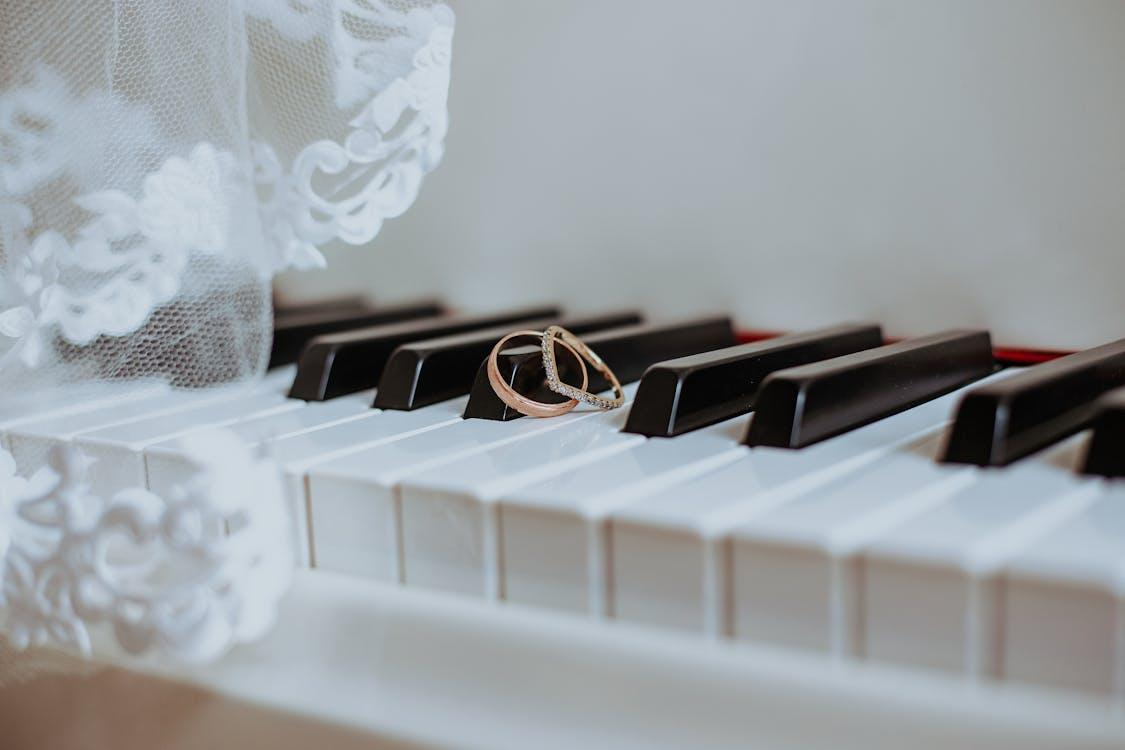 Wedding rings placed on a piano keyboard under a soft veil