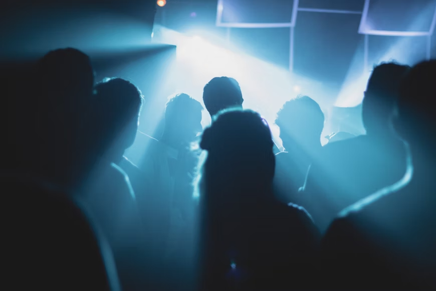 blue light spread across the room at a party with people's silhouettes