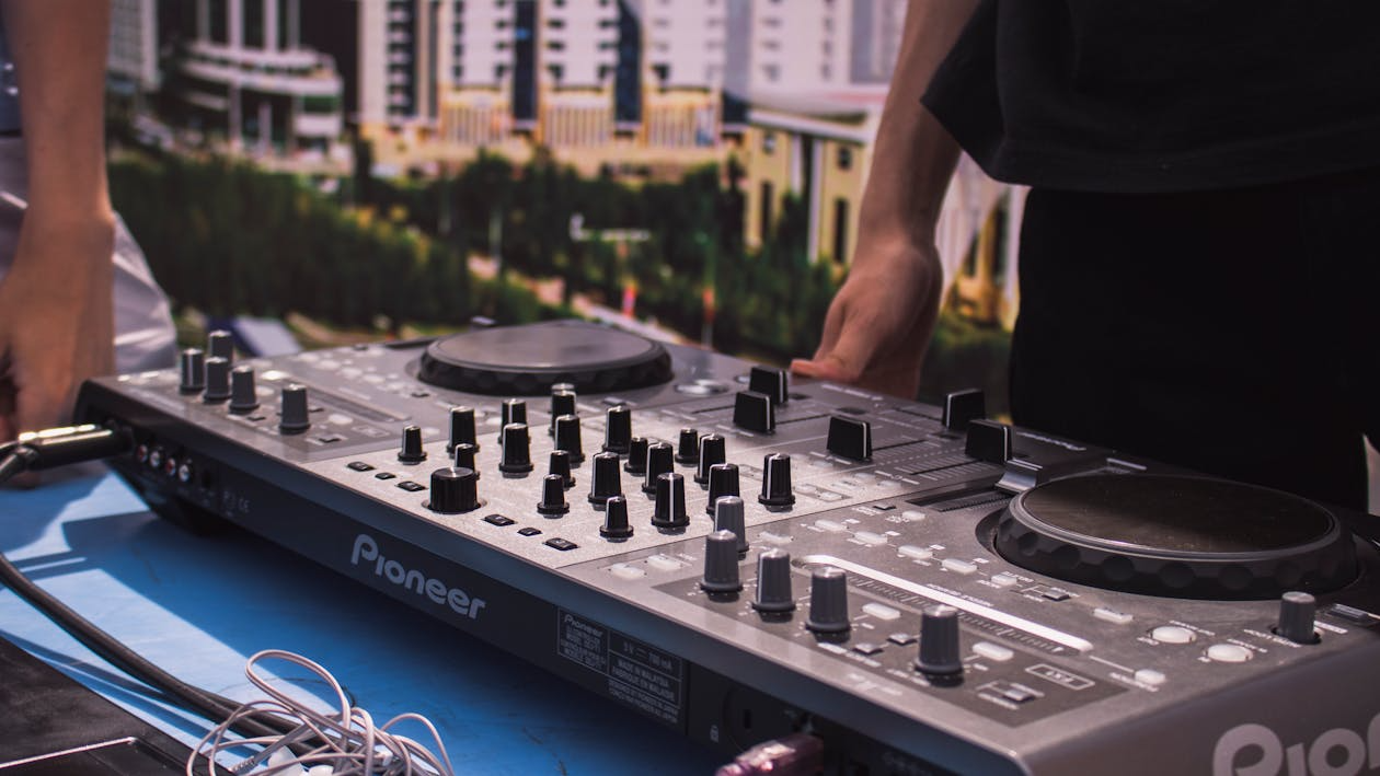 DJ controller with multiple knobs and turntables set up on a table at an outdoor event