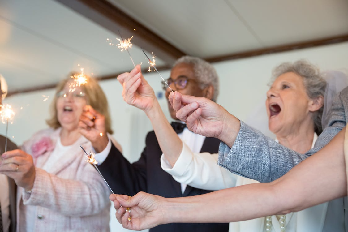 Group of adults holding sparklers and celebrating together during a festive indoor gathering