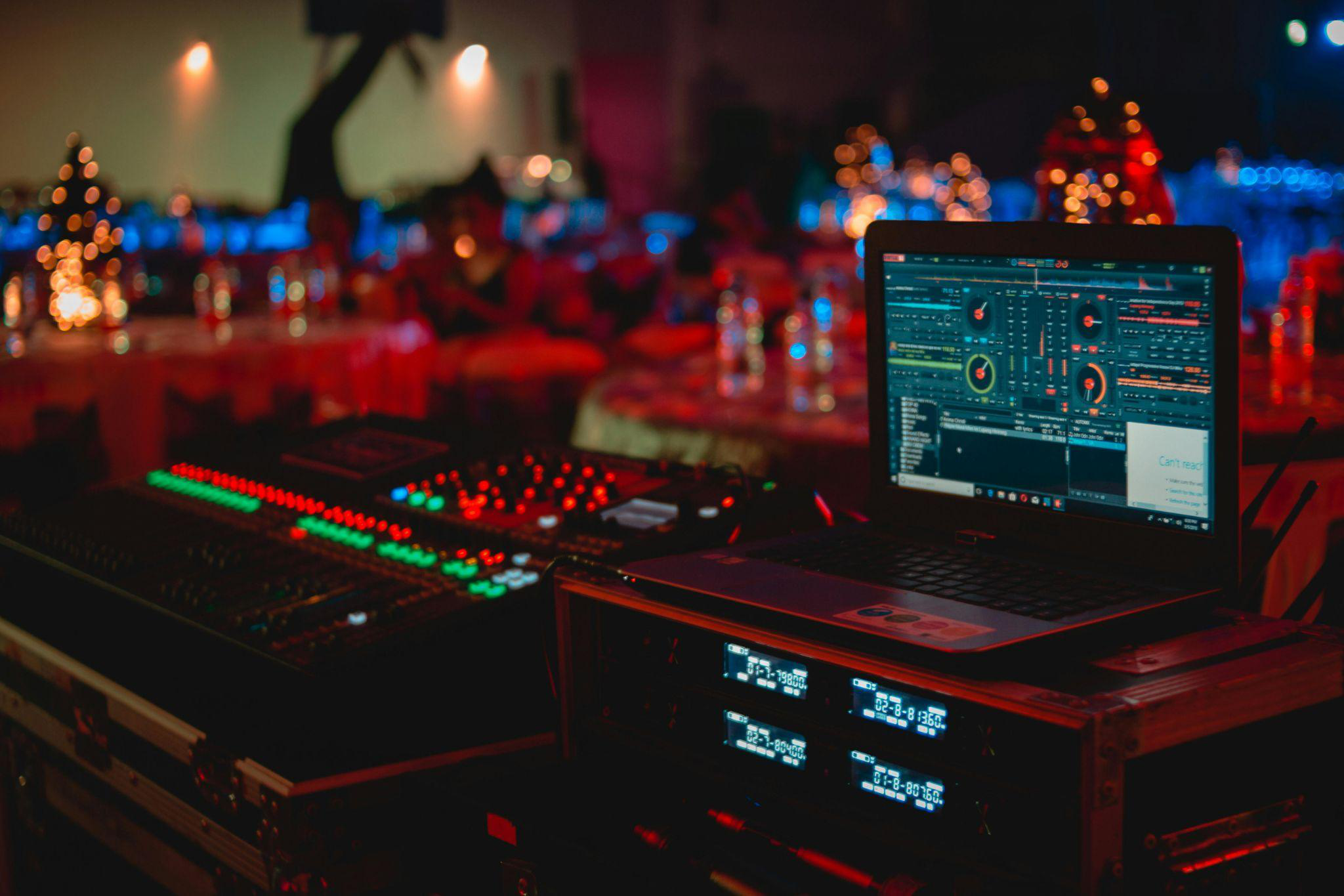 a DJ’s equipment setup at a brightly illuminated event